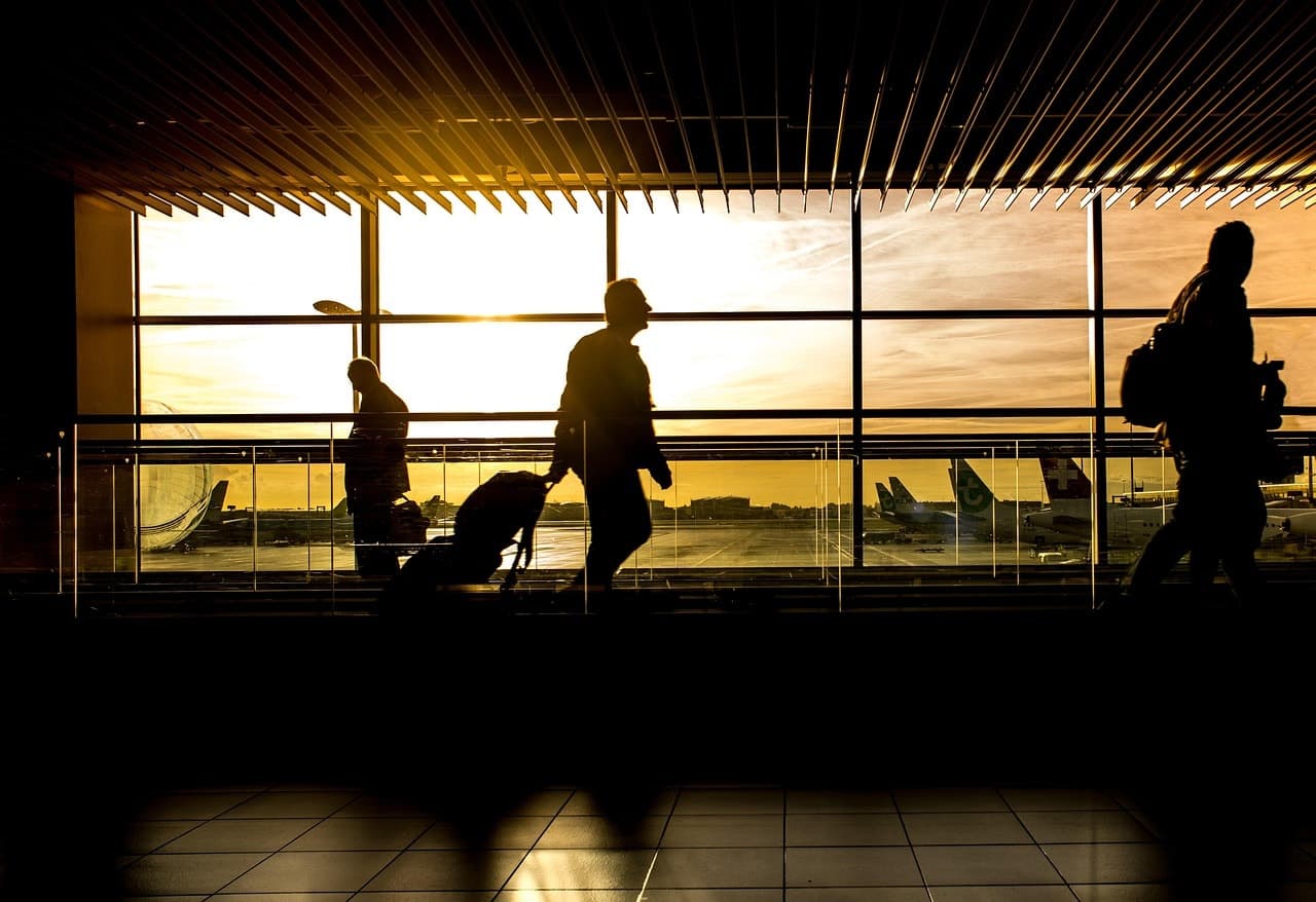 Silhouetted passengers walking towards departure gates at sunset