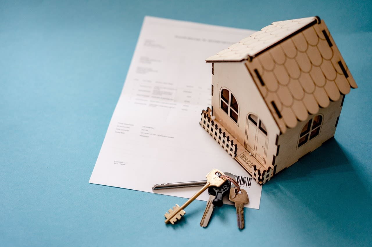 Documents, a model house and keys on a table