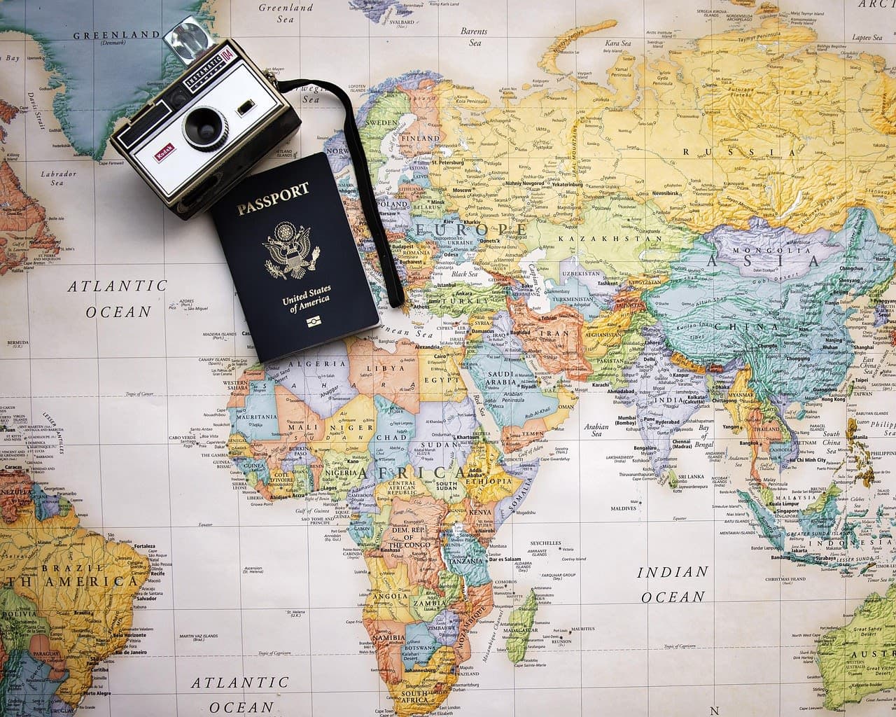 A passport and camera resting on a world map