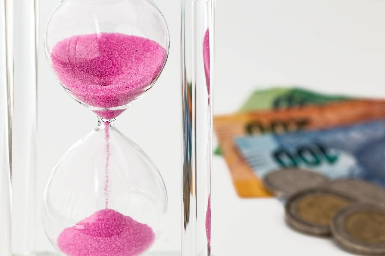 An hourglass beside coins and banknotes