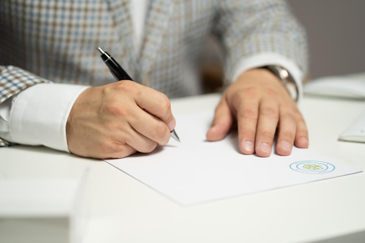 Hand signing a document at a desk